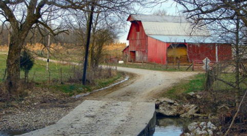 image of a red barn, gravel road, and two trees